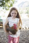 Chica sosteniendo pollo en el zoológico de mascotas - foto de stock