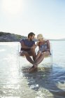 Couple sitting in chairs in waves — Stock Photo
