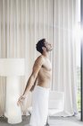 Uomo in asciugamano crogiolarsi alla luce del sole alla finestra della camera da letto — Foto stock