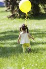 Girl carrying balloon in backyard — Stock Photo