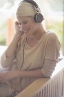 Woman listening to headphones on sofa — Stock Photo