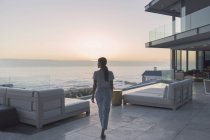 Frau zu Fuß auf Luxus-Haus Vitrine Außenterrasse bei Sonnenuntergang — Stockfoto
