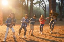 Students and teacher playing tug of war in forest — Stock Photo