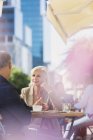 Geschäftsfrau hört Geschäftsmann im sonnigen städtischen Bürgersteig-Café zu — Stockfoto