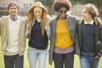 Glückliche junge Freunde, die zusammen im Park spazieren gehen — Stockfoto