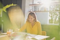 Woman drawing at sunny kitchen table — Stock Photo