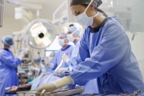Enfermera vistiendo uniformes que preparan instrumentos médicos en quirófano - foto de stock