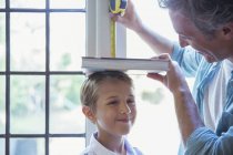 Father measuring son's height on wall — Stock Photo