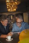 Homens usando tablet digital e beber café na mesa do restaurante — Fotografia de Stock