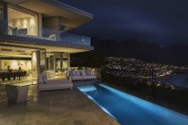 Illuminated luxury home showcase exterior with lap pool at night — Stock Photo