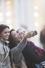 Друзья говорят фото с сотовым телефоном вместе на городской улице — стоковое фото
