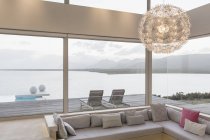 Сучасна розкішна домашня вітрина інтер'єру вітальні з люстрою та видом на океан — стокове фото
