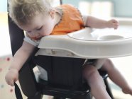 Baby girl playing in high chair — Stock Photo