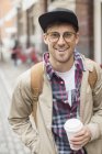 Чоловік з чашкою кави на міській вулиці — стокове фото