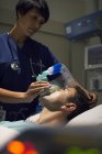 Médico feminino usando máscara anestesiando homem adulto médio na enfermaria do hospital — Fotografia de Stock
