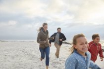 Веселая семья вместе бегает по пляжу — стоковое фото
