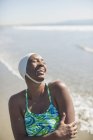 Woman in bathing suit and cap laughing on beach — Stock Photo