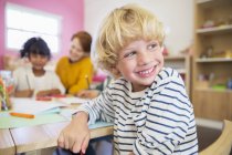 Учащийся улыбается в классе в помещении — стоковое фото