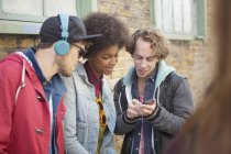 Friends using cell phone on city street — Stock Photo