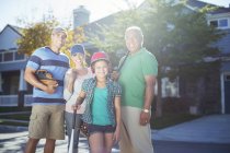 Portrait of smiling multi-generation family with baseball bat in street — Stock Photo