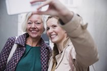 Sonriendo madre e hija tomando selfie con el teléfono de la cámara - foto de stock