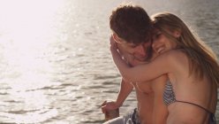 Прихильна молода пара обіймається на березі озера — стокове фото