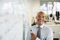 Businessman smiling at whiteboard in office — Stock Photo