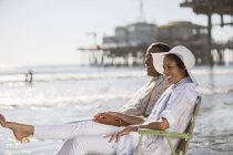 Casal relaxante em cadeiras de gramado na praia — Fotografia de Stock