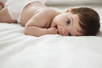 Entzückendes kleines Mädchen auf dem Bett liegend — Stockfoto