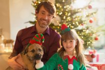 Porträt lächelnder Vater, Tochter und Hund vor dem Weihnachtsbaum — Stockfoto