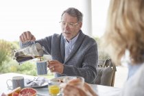 Senior man pouring coffee from French Press on patio — Stock Photo