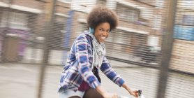 Happy young woman riding bicycle on city street — Stock Photo