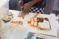 Junge Köchin schneidet Lachs und macht Sushi im Restaurant — Stockfoto
