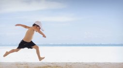 Garçon ludique courir sur la plage tropicale — Photo de stock