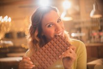 Portrait woman with sweet tooth craving biting into large chocolate bar — Stock Photo