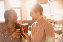Smiling couple drinking beer in bar together — Stock Photo