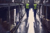 Вид сзади на рабочих, идущих в проходе распределительного склада — стоковое фото
