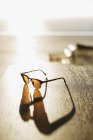 Солнечные очки отбрасывают тень на стол — стоковое фото