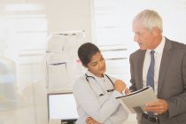 Female doctor and male hospital administrator reviewing paperwork — Stock Photo