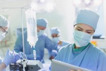 Chirurgin trägt OP-Maske mit digitalem Tablet im Operationssaal — Stockfoto
