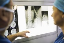 Dos doctores maduros discutiendo las radiografías y resonancias magnéticas del paciente - foto de stock