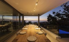Tavolo da patio in legno illuminato con placesettings al tramonto — Foto stock