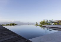 Tranquil luxury infinity pool with mountain view below blue sky — Stock Photo