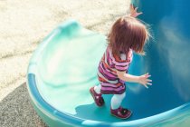 Menina bebê escalada slide no parque infantil — Fotografia de Stock