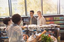 Jóvenes amigos hablando en el mercado de comestibles - foto de stock