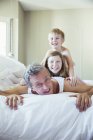 Père et enfants jouant au lit — Photo de stock