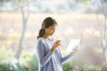 Woman drinking orange juice and using digital tablet — Stock Photo