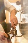 Imagen recortada de barista presionando espresso, utilizando la máquina de espresso - foto de stock