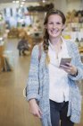Ritratto donna sorridente sms con cellulare in negozio — Foto stock