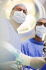Vista de ángulo bajo de médicos maduros realizando cirugía - foto de stock